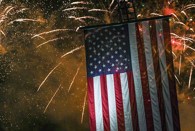 Fireworks blast near a U.S. flag displayed on a Williamston fire ladder truck, during the 4th of July Freedom Celebration Fireworks and Concert in Williamston, S.C. Saturday, June 29, 2024.