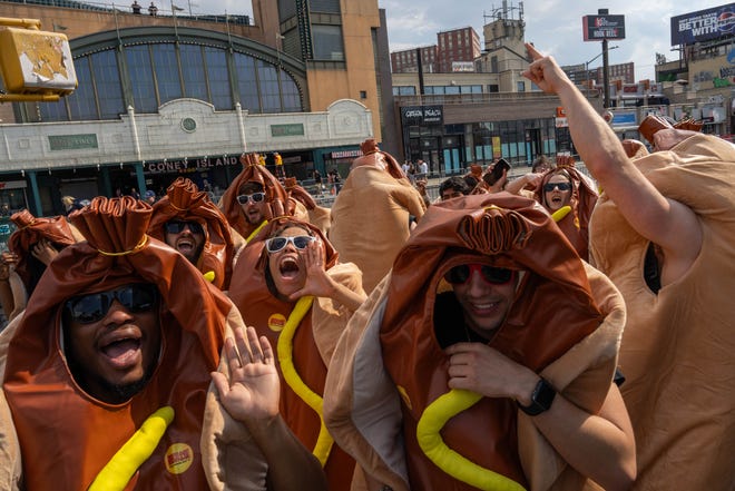 People dressed in hot dog costumes cheer before Nathan's Annual Hot Dog Eating Contest on July 4, 2024 in New York City. Sixteen-time winner Joey Chestnut is banned from this year's contest due to his partnership with Nathan's competitor Impossible Foods, which sells plant-based hot dogs.