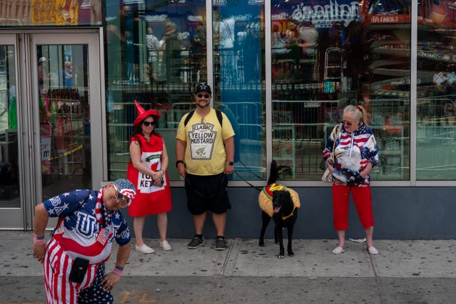 People in costumes, including a dog dressed as a hot dog, wait for the start of Nathan's Annual Hot Dog Eating Contest on July 4, 2024 in New York City.