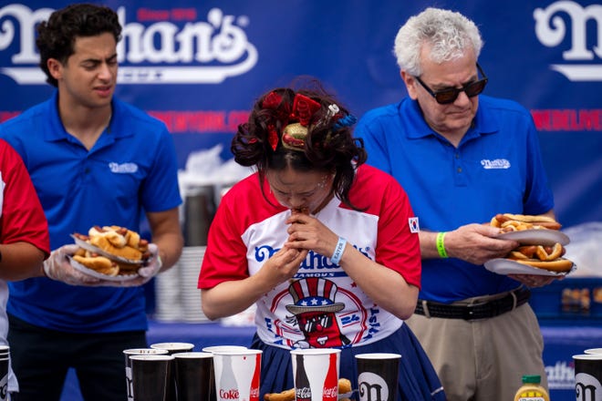 Competitors compete for the women's title at Nathan's Annual Hot Dog Eating Contest on July 4, 2024 in New York City. Sixteen-time winner Joey Chestnut is banned from this year's contest due to his partnership with Nathan's competitor Impossible Foods, which sells plant-based hot dogs.