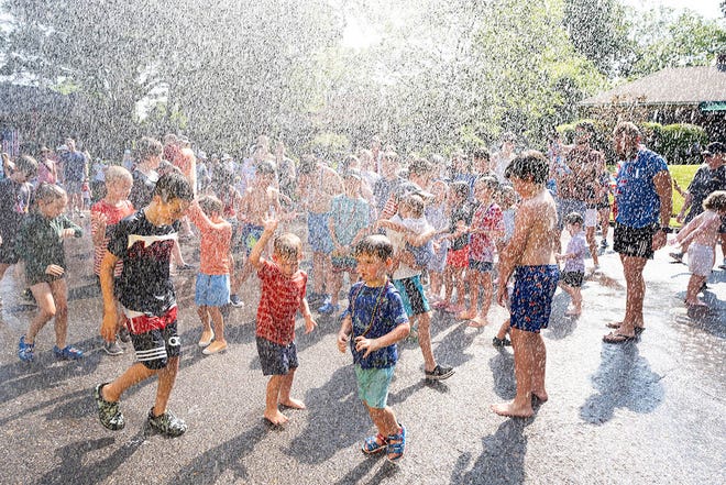 Children and parents frolic in the water sprayed from a Memphis Fire Department fire truck during the 75th Annual High Point Terrace Neighborhood Independence Day Celebration in Memphis, Tenn., on Thursday, July 4, 2024.