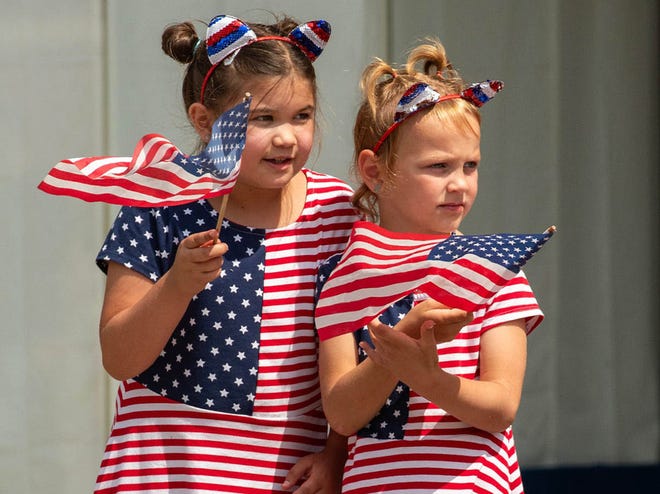 Sisters Jaelynn McMiller, 8, and Madelynn Racine, 5, watch the Fitchburg (Mass.) Fourth of July Parade on Main Street Thursday.