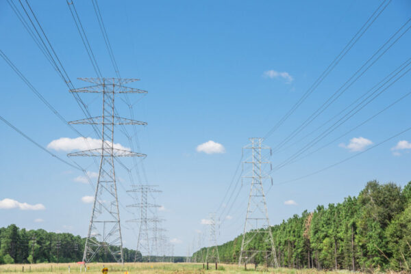 Parallel rows of transmission towers (power tower, electricity pylon, steel lattice tower) cloud blue sky in Houston, Texas, US.