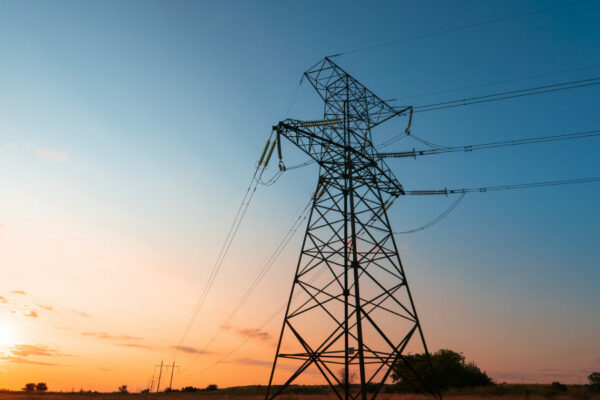 The silhouette of the evening electricity transmission pylon. Power transmission from a power plant to a city