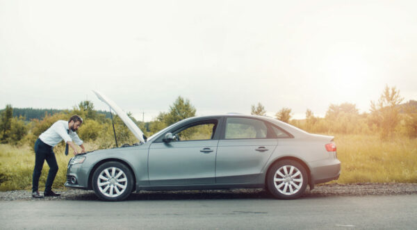 Businessman examining broken down car